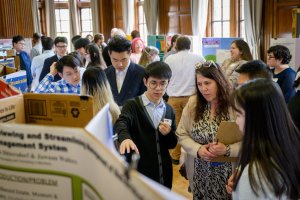 An image of many students and others learning about projects presented on posters, from a previous exposition