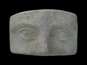Rectangular piece of clay with a rendering of two eyes and a nose.