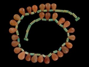 Necklace strung with oblong faience and tear-shaped carnelian beads.