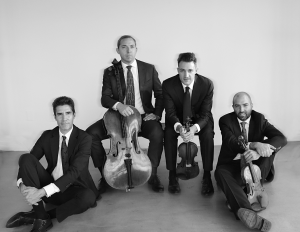 The members of the Escher Quartet - four men - are seated wearing suits and ties in a black and white photo.