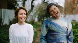 Caroline Shaw and Gabriel Kahane next to each other outside smiling.