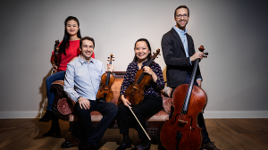The four members of Rosamunde string quartet sit posed with their instruments.
