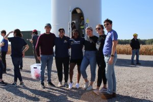 A group of students poses in front of a wind turbine