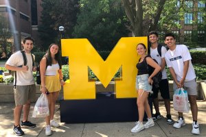 Students standing beside the library's giant block M.
