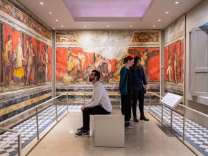 Three people look at the Kelsey Museum’s Villa of the Mysteries watercolor reconstruction.