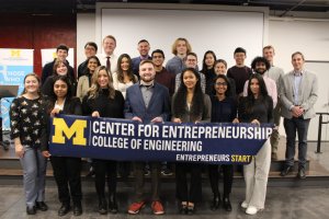 Members of ELP pose for a group photo. Twenty-one students and two staff members smile while holding a banner that reads "Center for Entrepreneurship. Start here."