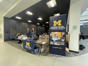 Two people standing behind a table covered in swag and goodies for folks to grab.