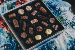 Box of chocolates lays on a blue and white tablecloth