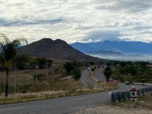 Highway winding through scenic mountains with a cloudy sky above