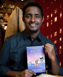 Image of author, Omar Mohamed holding his graphic novel