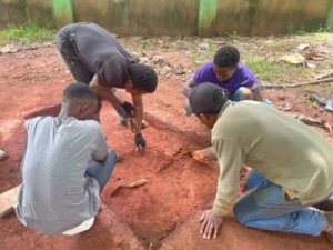 Four archaeologist closely examine a 2'x4' dig section