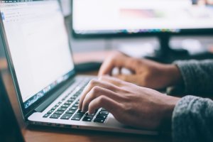 Hands typing on a laptop computer.