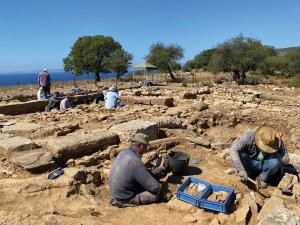 Researchers at Notion excavate among the stone foundations of a structure.