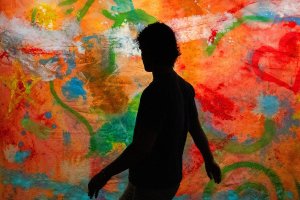 The Stampede: a figure is silhouetted in front of a colorful background image