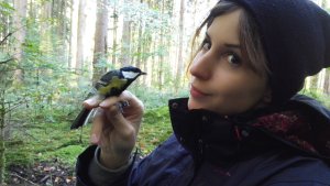 Kasja Malkoc holding a bird in a forest