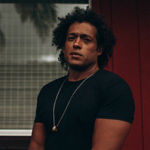 Makaya McCraven in black tshirt with gold ring on silver necklace