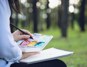 Person sitting outside holding a watercolor set