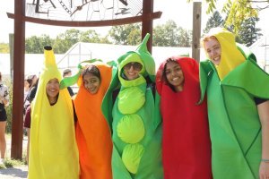 Five people dressed as a banana, a carrot, pea pod, tomato, and corn cob
