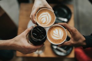 three hands holding cups of coffee