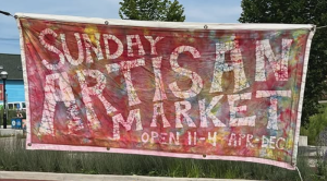 An outdoor banner with text: Sunday Artisan Market, Open 11-4, Apr-Dec