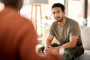 Man sitting with his hands together in front of him, looking at person off-screen.