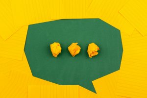 orange sheets of paper lie on a green school board and form a chat bubble with three crumpled papers. orange sheets of paper lie on a green school board and form a chat bubble with three crumpled papers.