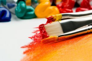 Paint brush on yellow, orange, and red painted canvas