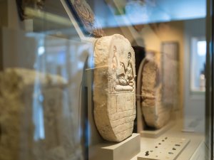 A case in the Kelsey Museum’s Egyptian gallery full of funerary objects. Prominently featured is a carved stone stele.
