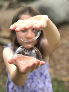 Child in purple dress playing with bubbles between their hands Child in purple dress playing with bubbles between their hands