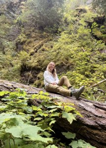 A woman sitting on a log in a lush forest A woman sitting on a log in a lush forest