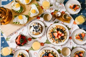 Table with white table cloth with plates of various breakfast foods