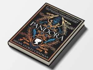 The cover of the novel “Pandora” by Susan Stokes-Chapman, featuring gold, blue, and white illustrations of a Greek jar, swirling foliage, keys, birds, and a silhouette of a woman’s face.