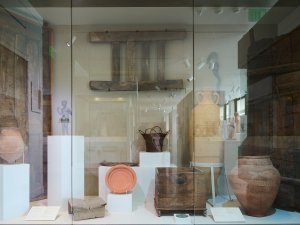 View of the Kelsey Museum’s Karanis display case showing such household objects as doors, ladders, boxes, stools, pottery, baskets, and figurines.