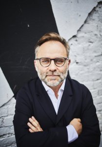 A portrait image of the spaker in a white shirt and black blazer.