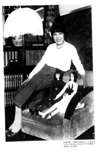 An old black and white photo of Yoshiya Nobuko posing with two large dolls