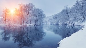 winter sunrise through trees and over a snowy river