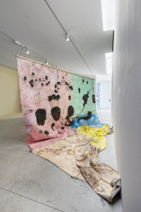 A large abstract painting on a canvas draped across a gallery floor.