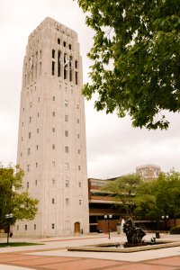 Bronze fountain spraying water, sidewalks, trees, grass, carillon tower