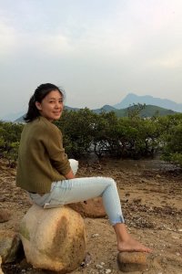 Speaker Bendi Tso sitting on a rock looking back at the camera