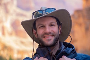 Man in a hat smiles at the camera