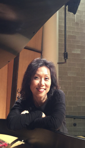 Headshot of Moon-Sook Park leaning over a piano
