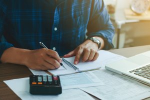 Picture of someone's hands and a calculator sitting on a desk