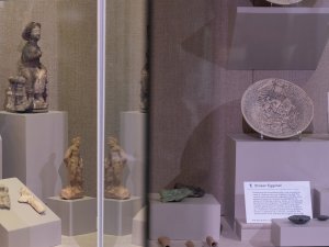View into a museum case containing objects from Seleucia-on-the-Tigris, Iraq, including figurines and a demon bowl covered in inscriptions.