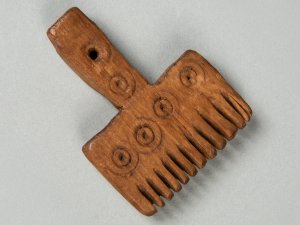 Small wooden weaving comb decorated with lines of concentric circles.