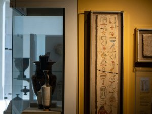 View of the Kelsey Museum’s gallery showing a panel of a limestone false door on display. The long, skinny panel has two columns of hieroglyphs, painted with red, blue, green, yellow, and black pigments.