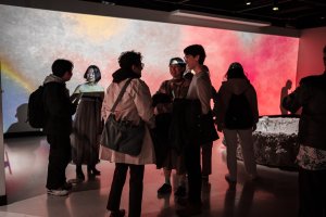 Visitors, bathed in red projected light, gathered at the 2025 MFA Thesis exhibition