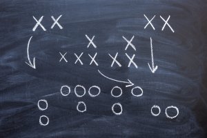A chalkboard football play outline with Xs and Os.