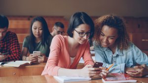 Students are talking and laughing sitting at desks at university.