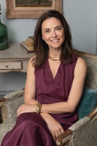 Jennifer Wallace: woman with long dark hair, smiling, sitting in a chair.