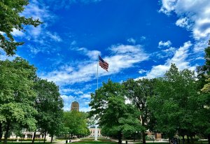 Photograph of University of Michigan diag with flag pole centered, in the background is a blue sky with white clouds